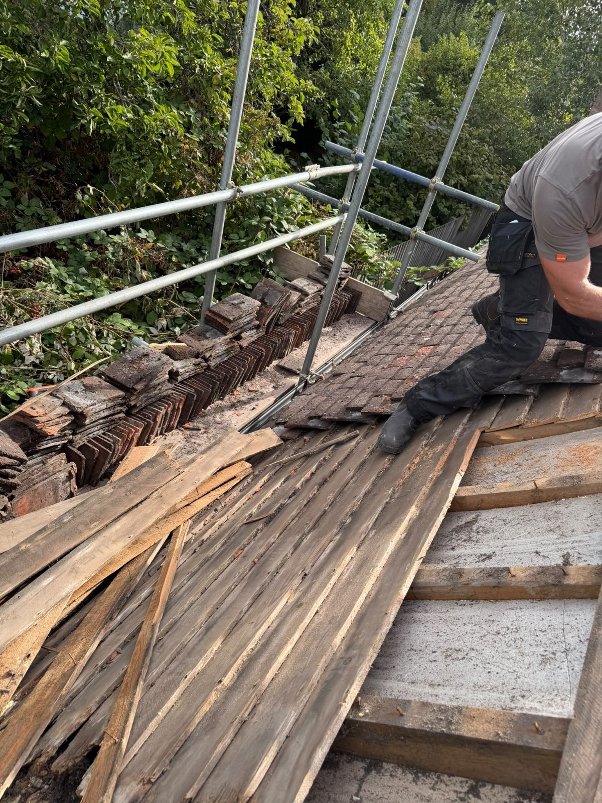A roofer stripping back an old roof for J P Building Services