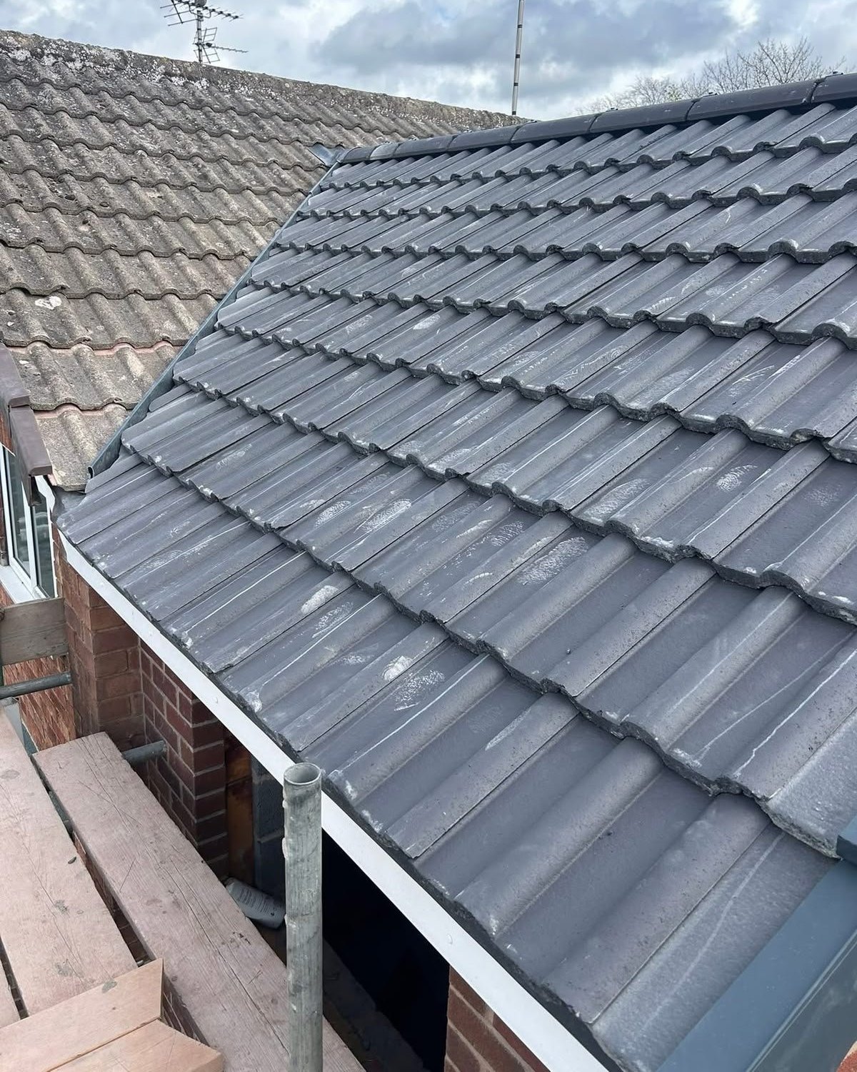 A roofer repairing slipped tiles on a pitched roof