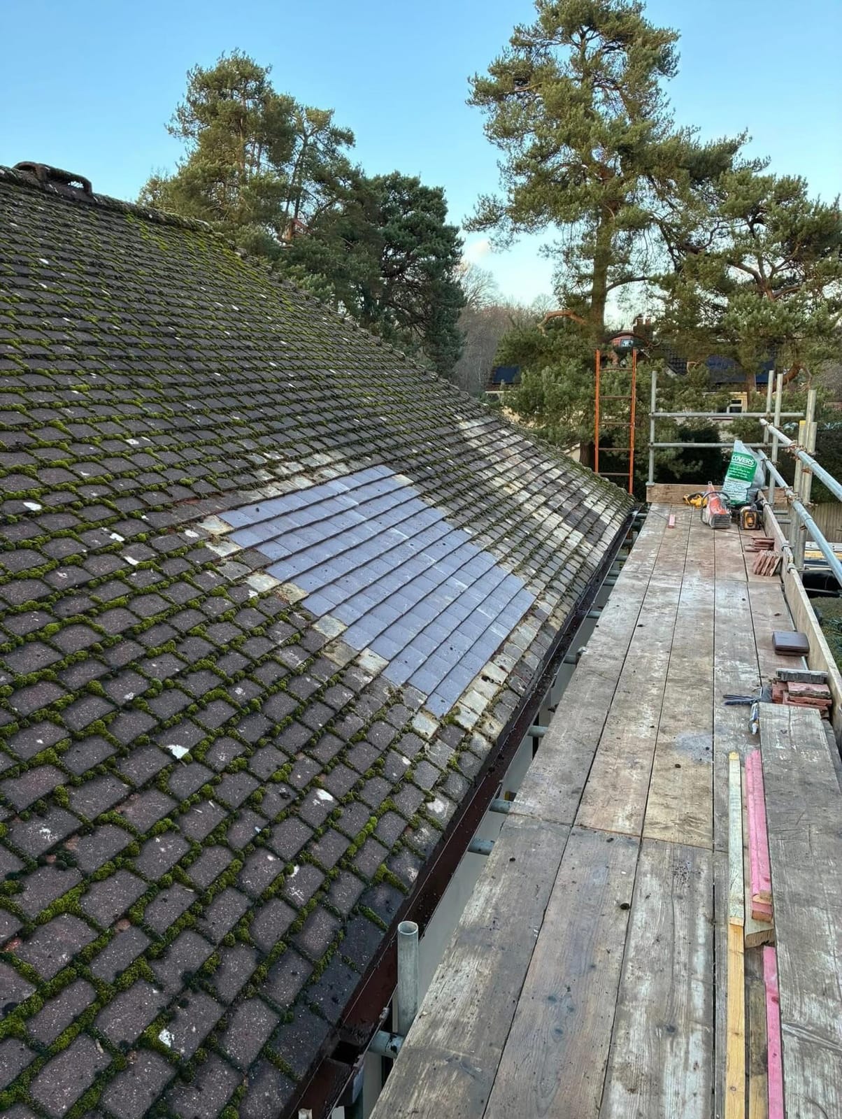 A roofer repairing slipped tiles on a pitched roof